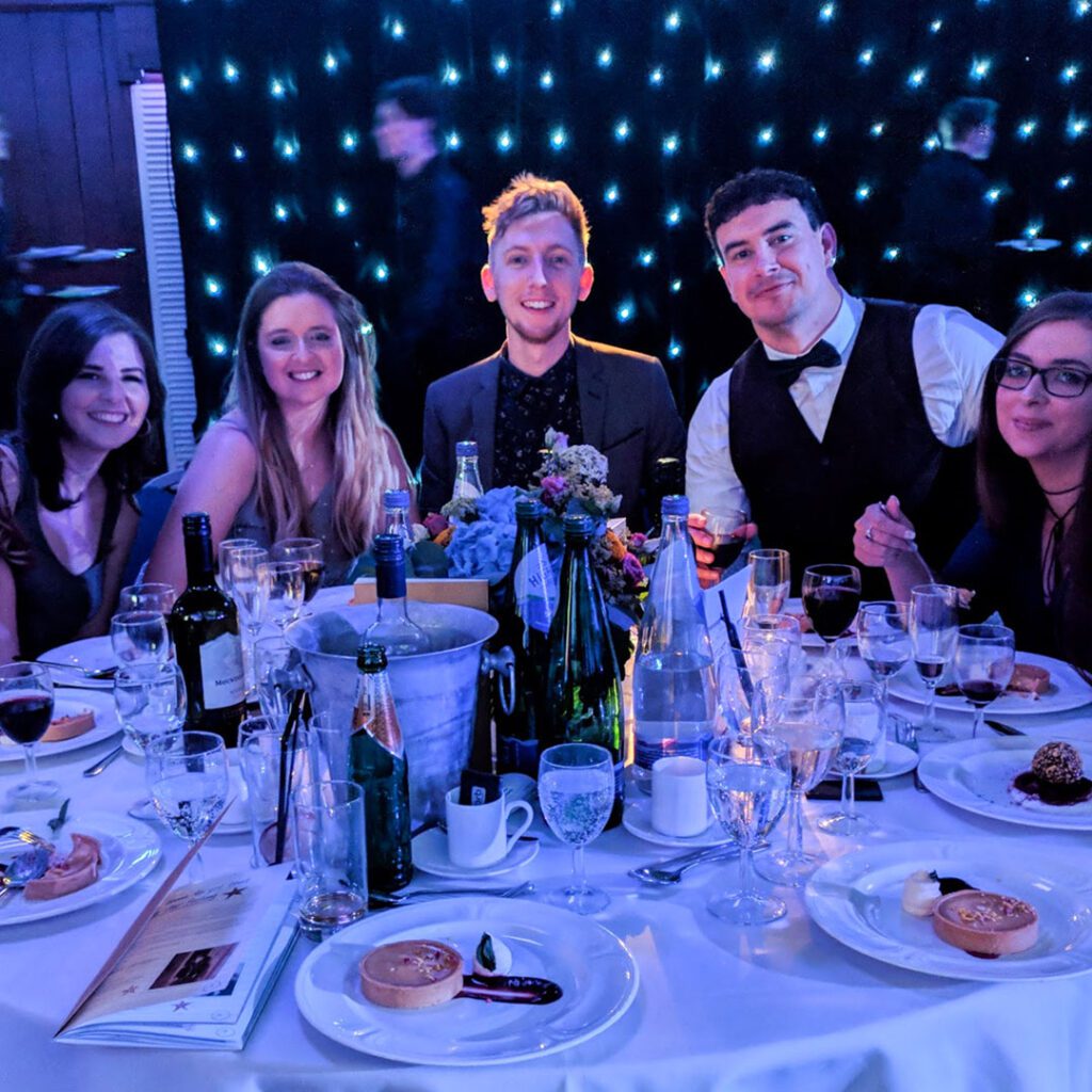 A team around the table at an awards ceremony, with Chris at the centre.