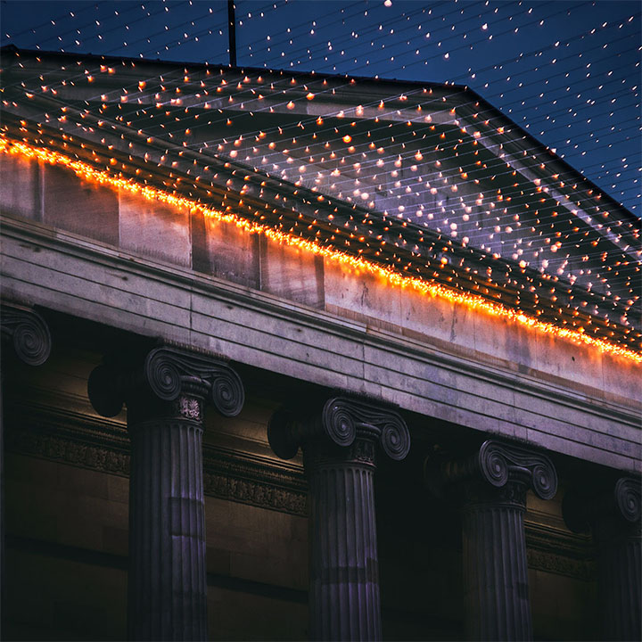 An unedited photo of a building in Glasgow at night, with fairy lights.