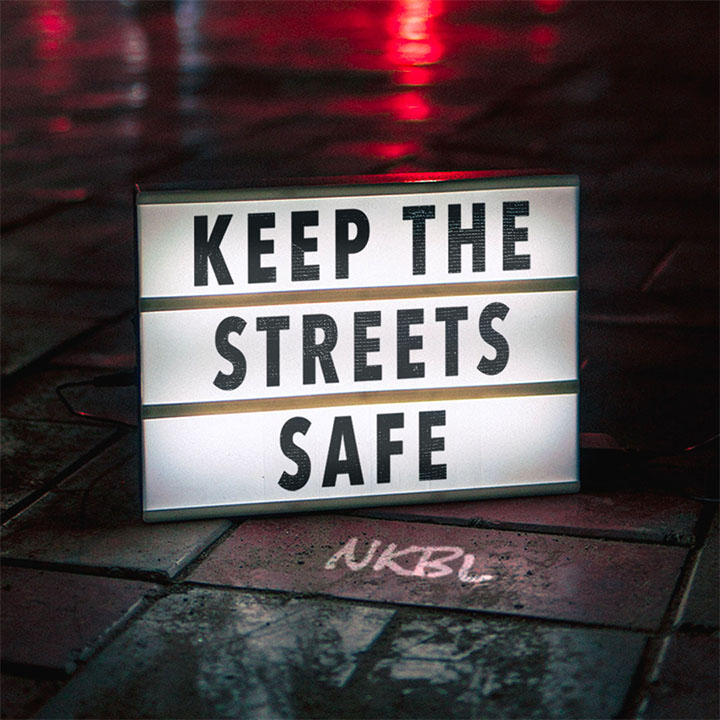 A retouched image of the same lightbox, now saying keep the streets safe". It has NKBL in chalk edited onto the sidewalk.