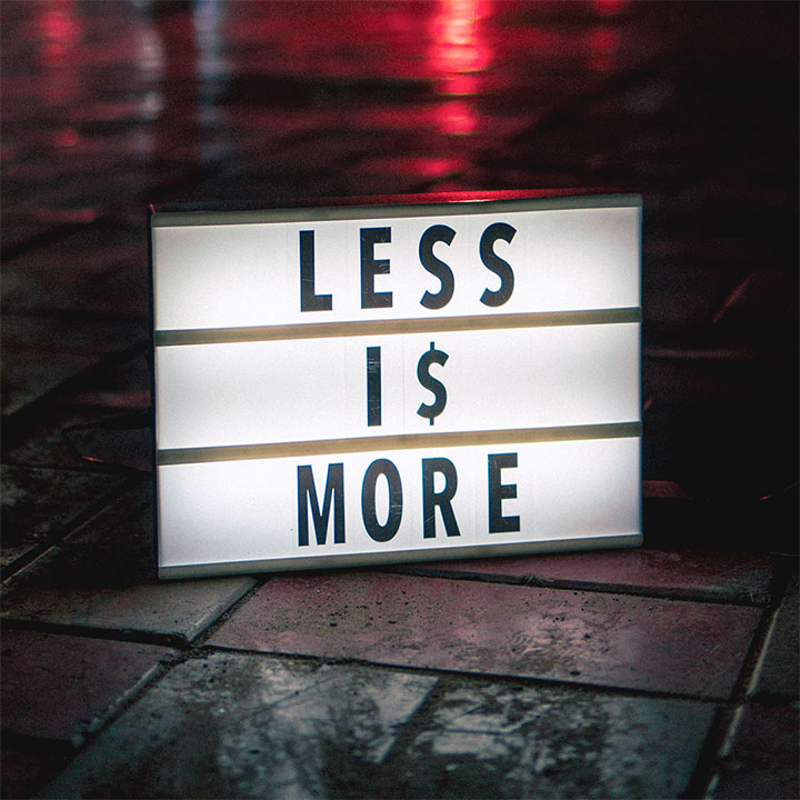 An unedited photo of a lightbox on a dark street, with the original text saying less is more.