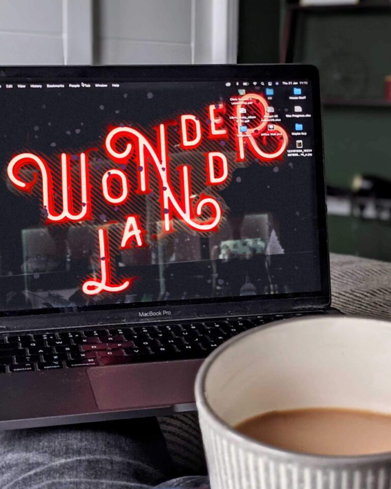 An open laptop and cup of coffee, with the word Wonderland as the desktop background.