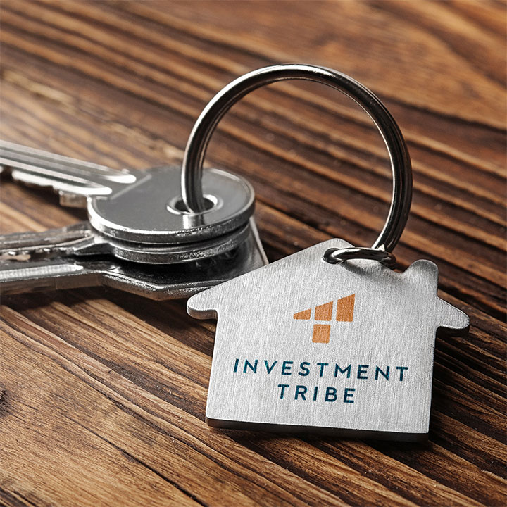 A retouched image of keys, with the Investment Tribe logo edited onto a house shape keyring.